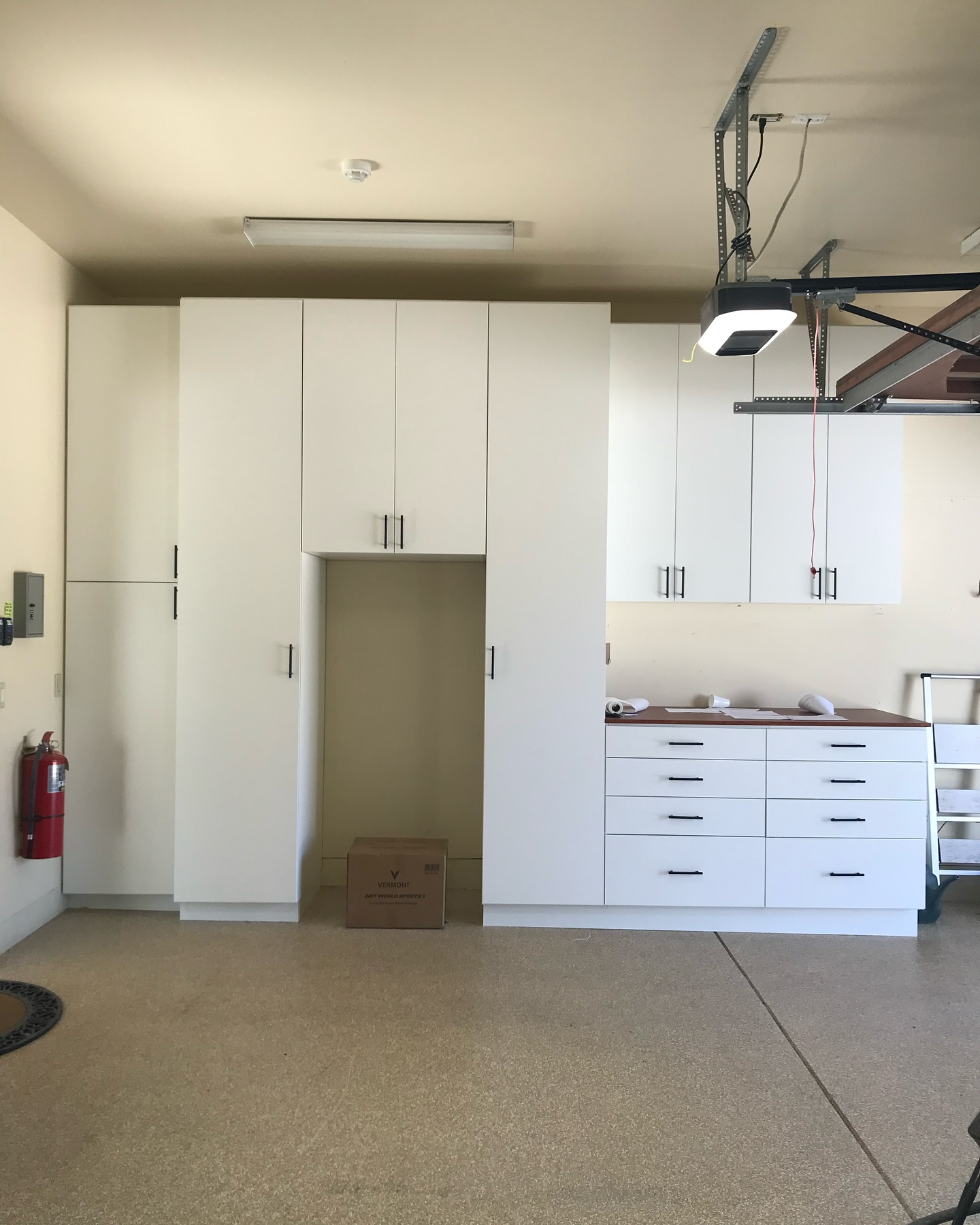 Floor-to-ceiling white garage cabinetry with workspace
